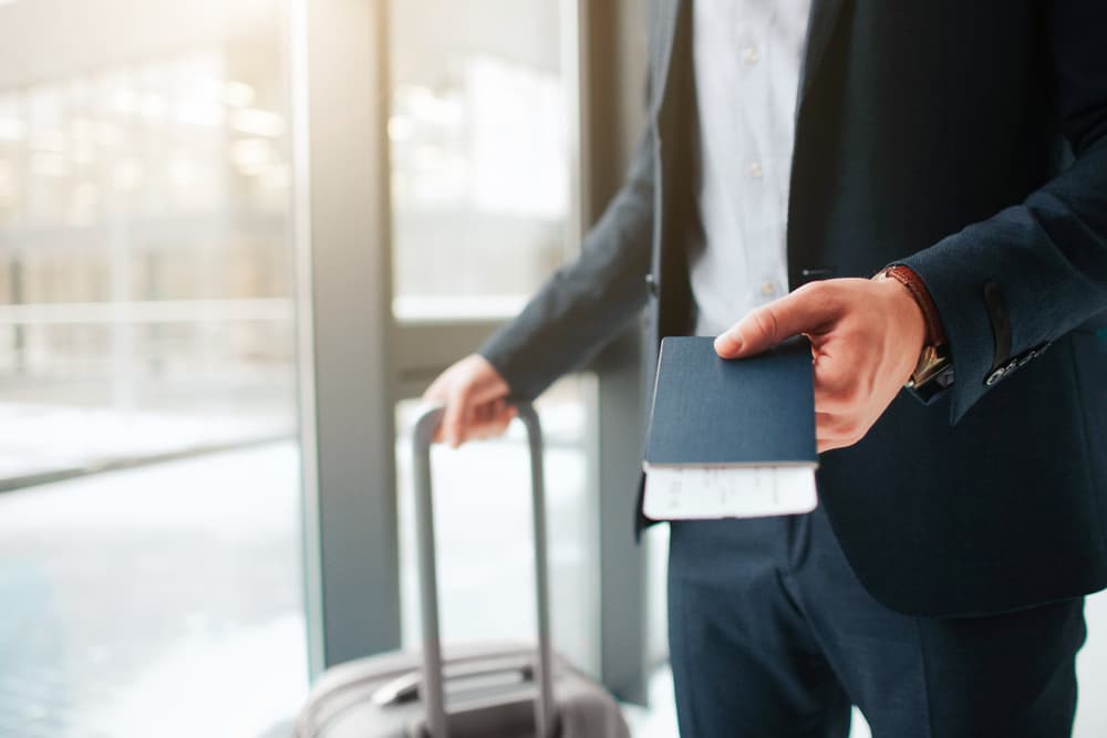 Man stand at airport, holds passport with ticket for international travel