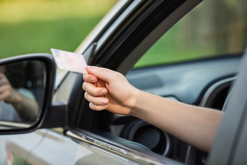 person hand out of the car window holding the driver license