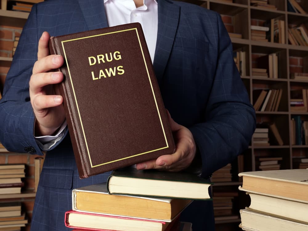 Attorney holds DRUG LAWS book. 