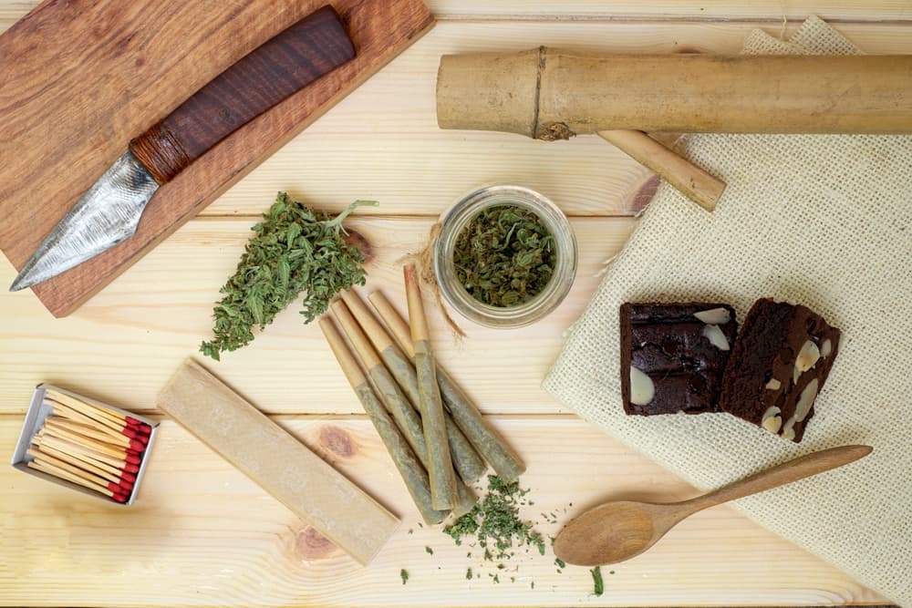 Marijuana and drug paraphernalia on a wooden background.