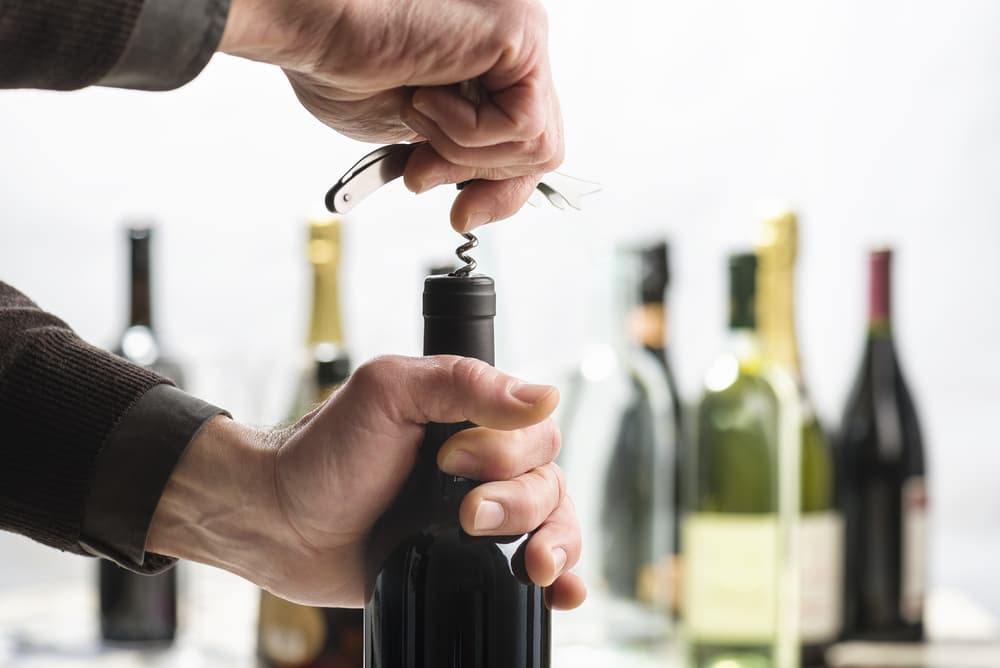 Using a corkscrew to open a bottle of wine.