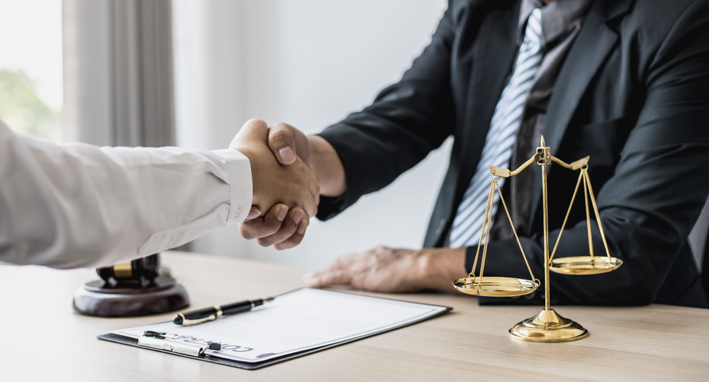 Lawyer and client shake hands, after winning a lawsuit where a lawyer hired by a client in a fraud case and proceeding in a fair and correct manner, the client wins the case. Fraud litigation concept.