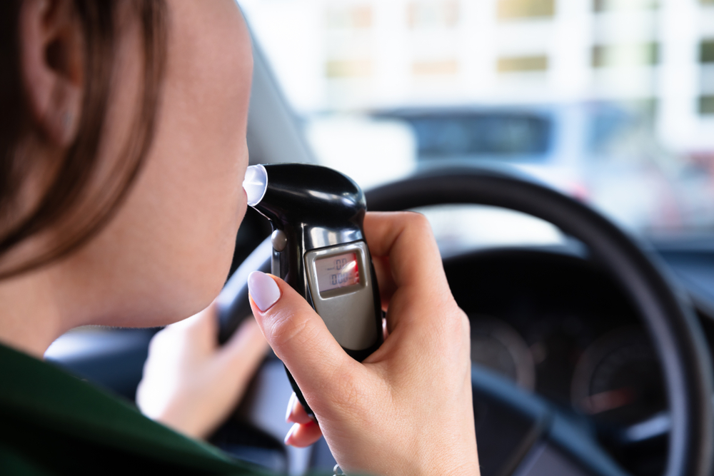 Close-up of a woman's mouth as she takes an alcohol breathalyzer test.