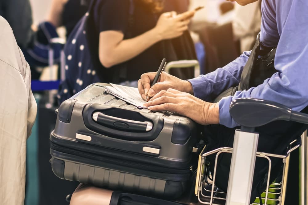 Male tourist hand filling Immigration form on flight.