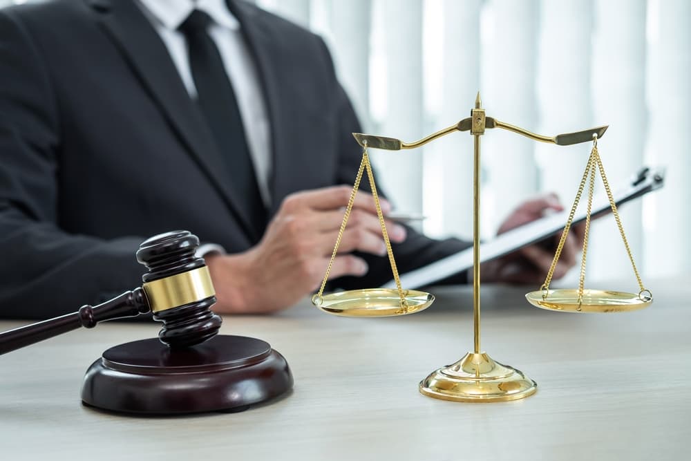 A male lawyer reviewing legal case documents in his office, highlighting themes of law and justice, with a focus on attorney-client interactions and lawsuits.






