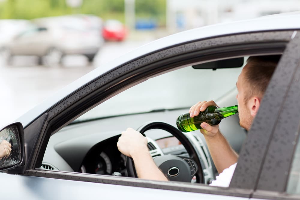 Transportation and vehicle safety concept: a man consuming alcohol while driving a car.






