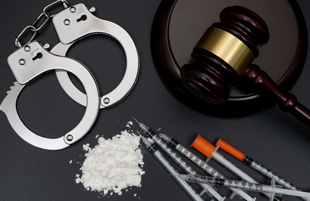 Concept of drug crime featuring white powder and a disposable syringe on a black background.






