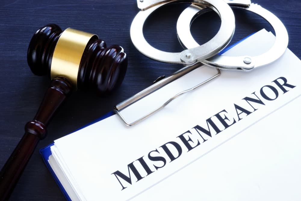 The image of the legal documents titled "MISDEMEANOR" along with the gavel on the desk, symbolizing law and justice.