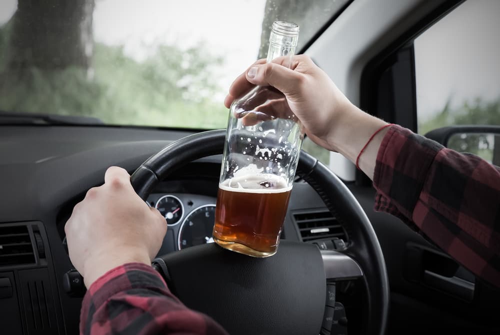 A man drinking behind the wheel, highlighting the dangers of drunk driving and the potential for accidents due to alcohol abuse.