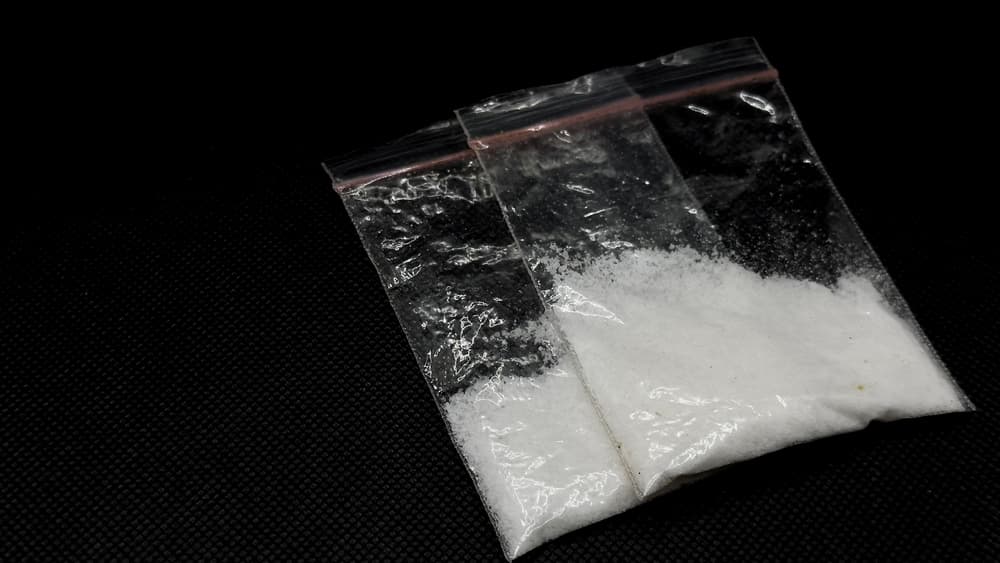 Methamphetamine packaged in clear plastic, set against a black background. This illustration highlights its use in illegal transactions.