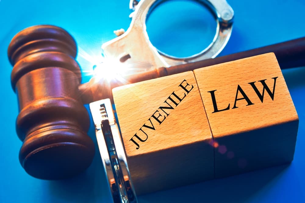 Juvenile law" word with gavel and handcuffs on a blue background